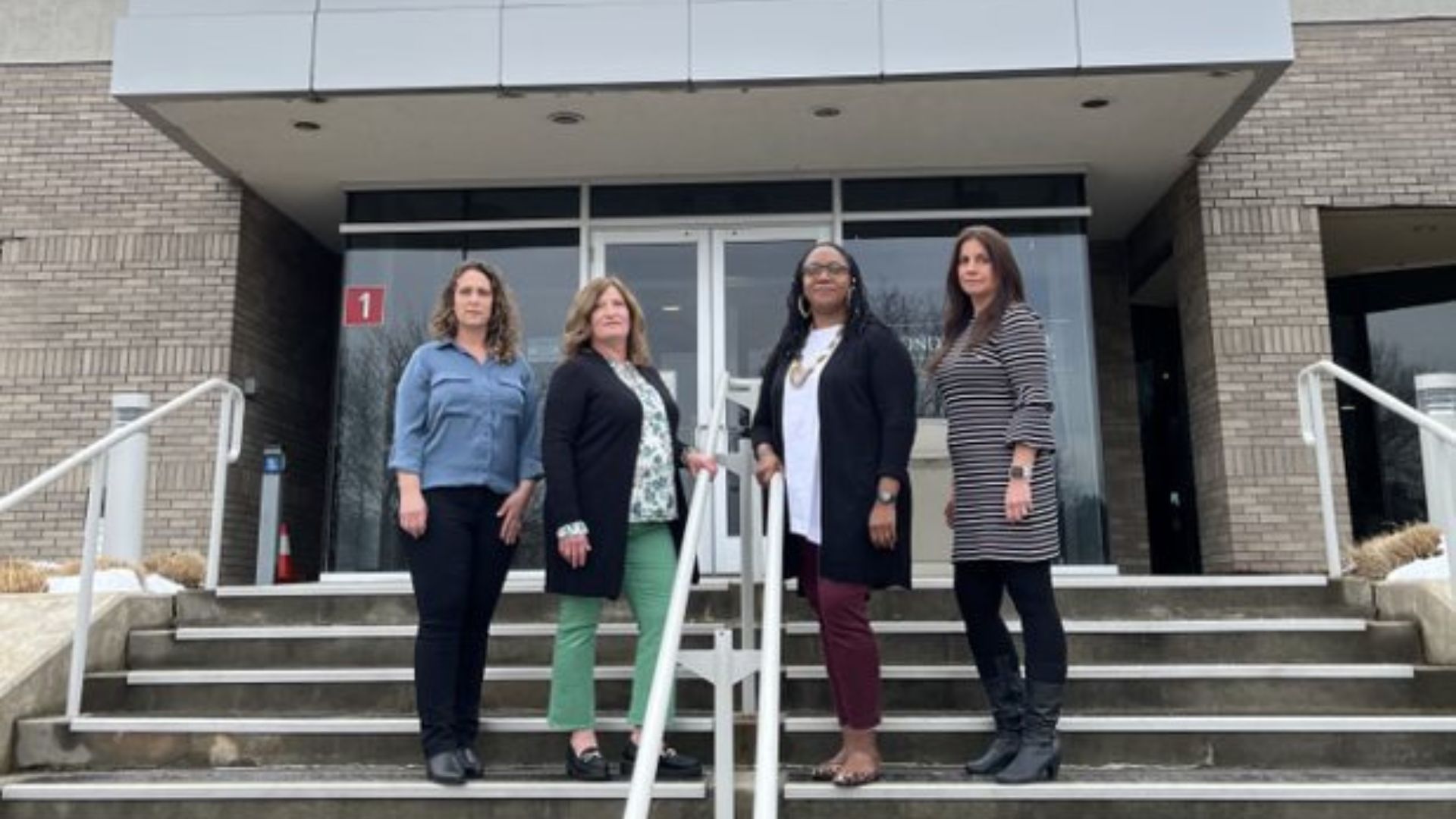 Four female scientists who work with Polycultural Centre of Excellence, standing in front of the building 