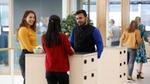 Three people talking near lockers in an office space.