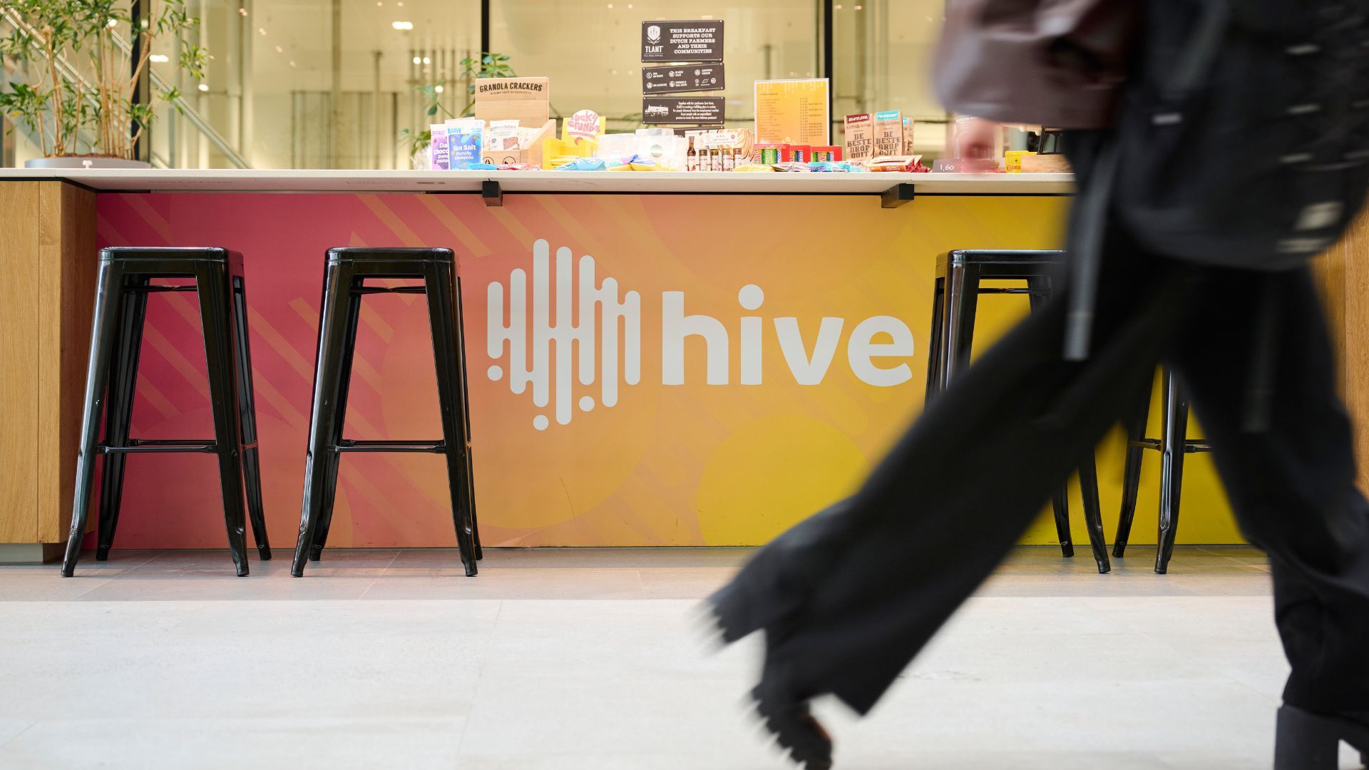 Person walking past counter with 'Hive' logo.