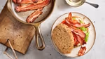Top view of sandwich placed on a plate with a pan of bacon on the side.