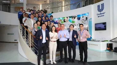 Reginaldo Ecclissato smiling with a team of colleagues on a staircase
